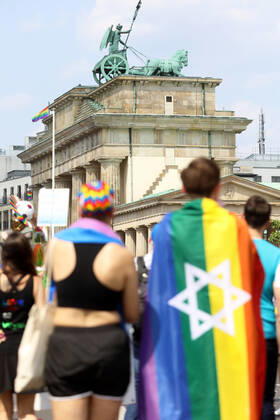 Berliner CHRISTOPHER STREET DAY 2021 - CSD - Am 24. Juli 2021 zieht der CSD in Berlin unter dem Motto SAVE OUR COMMUNITY SAVE YOUR PRIDE zum 43. Mal durch die Hauptstadt. Demoteilnehmer vor dem Brandenburger Tor trägt Regenbogenflagge mit Davidstern. Die bunte CSD-Parade startete in diesem Jahr als Demonstration an der Leipziger Straße, führte über den Potsdamer Platz, vorbei am Denkmal für die im Nationalsozialismus verfolgten Homosexuellen zum Brandenburger Tor und über die Siegessäule zur Urania. Aufgrund der Corona-Pandemie fand die Demonstration ausschließlich unter Einhaltung der vom Berliner Senat erlassenen Vorgaben statt. Die in den Vorjahren übliche Abschlusskundgebung musste daher ausfallen.
