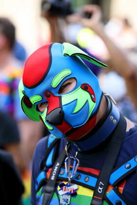 Berliner CHRISTOPHER STREET DAY 2021 - CSD - Am 24. Juli 2021 zieht der CSD in Berlin unter dem Motto SAVE OUR COMMUNITY SAVE YOUR PRIDE zum 43. Mal durch die Hauptstadt. Schwule Fetisch- und Lederszene im Demozug. Teilnehmer der Lederszene trägt Regenbogenflagge auf der Brust, ein Halsband und eine rot-blau-grüne Ledermaske. Die bunte CSD-Parade startete in diesem Jahr als Demonstration an der Leipziger Straße, führte über den Potsdamer Platz, vorbei am Denkmal für die im Nationalsozialismus verfolgten Homosexuellen zum Brandenburger Tor und über die Siegessäule zur Urania. Aufgrund der Corona-Pandemie fand die Demonstration ausschließlich unter Einhaltung der vom Berliner Senat erlassenen Vorgaben statt. Die in den Vorjahren