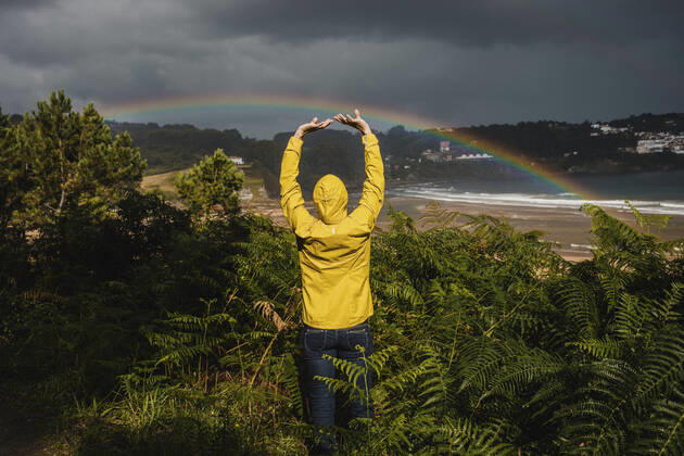 IMAGO Creative: Ende des Sommers Rear view of woman with raised arms by plants during rainy season model released Symbolfoto DMGF00222