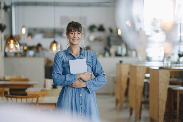 IMAGO Creative: Kreative Renaissance -- der junge Entrepreneur Happy female entrepreneur using digital tablet while standing in coffee shop model released Symbolfoto property released GUSF04624