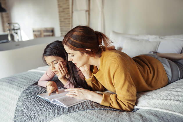 IMAGO Creative: Kulturelle Folgen der Pandemie: Gesundheitsbewußtsein und Alleinsein Mother and daughter reading book while lying on bed at home model released Symbolfoto property released JSMF01856