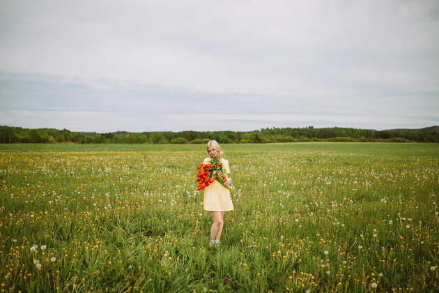 Content female in dress standing with bunch of red tulip flowers in meadow in summer CamilleGirard_GirlWithTulips_16.jpg Copyright: xCamillexGirardx Model Released
