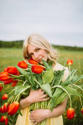 Content female in dress standing with bunch of red tulip flowers in meadow in summer CamilleGirard_GirlWithTulips_17.jpg Copyright: xCamillexGirardx Model Released