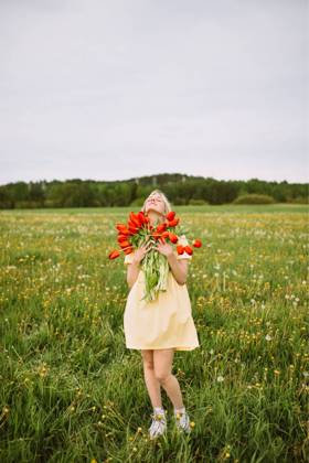 Content female in dress standing with bunch of red tulip flowers in meadow in summer with closed eyes CamilleGirard_GirlWithTulips_20.jpg Copyright: xCamillexGirardx Model Released
