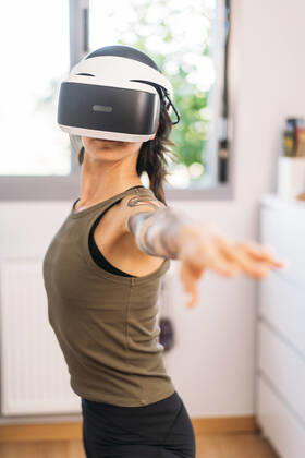 Mid adult woman using virtual reality headset while exercising at home model released Symbolfoto property released DAMF00885