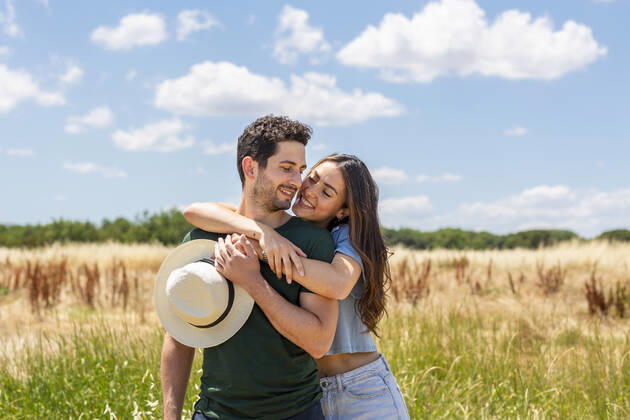 Smiling girlfriend embracing boyfriend at meadow on sunny day model released Symbolfoto EIF01632