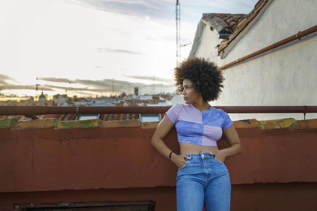 Young woman with hands in pockets standing on terrace model released Symbolfoto property released IFRF01059