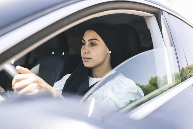 Young woman driving car model released Symbolfoto JCCMF03441