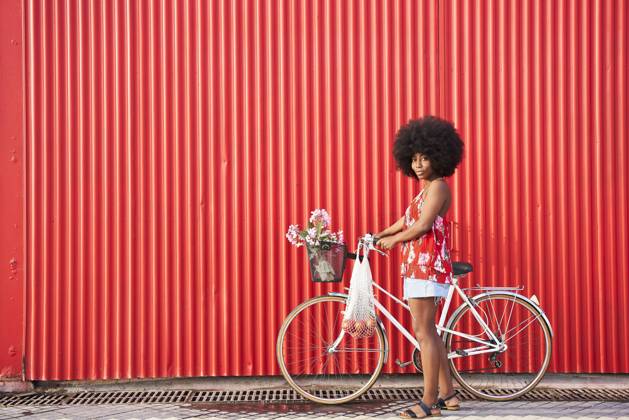 Afro woman with bicycle standing by red corrugated wall model released Symbolfoto VEGF04808
