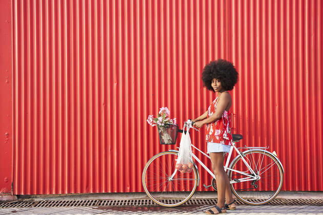 Afro woman with bicycle standing by red corrugated wall model released Symbolfoto VEGF04808
