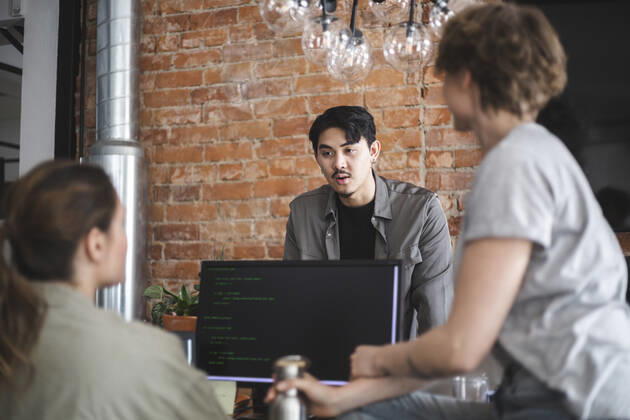 Male computer programmer discussing with female colleagues in office Sweden, Stockholm, model released, property released Copyright: xMaskotx , MA87890