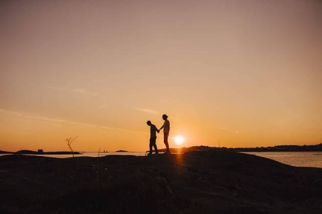 Male friends holding hands while walking at lakeshore during sunset Sweden, Gothenburg, model released Copyright: xMaskotx , MA88033