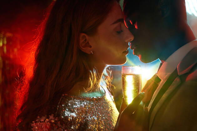 Side view of crop couple with glass on champagne in moment of kiss against shiny light ray looking at each other during party ManuelRuiz_NewYearsEvePartyCouple_33.jpg Copyright: xManuelxRuizx Model Released