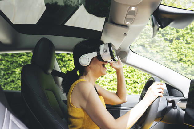 Excited woman wearing virtual reality simulator while driving electric car model released Symbolfoto JCCMF03738