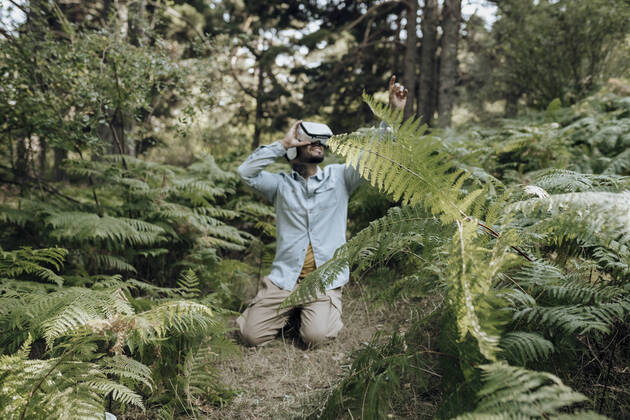 IMAGO Creative: Klimawandel - Zukunft und Innovation Man using virtual reality headset while kneeling in forest model released Symbolfoto property released JCCMF03788