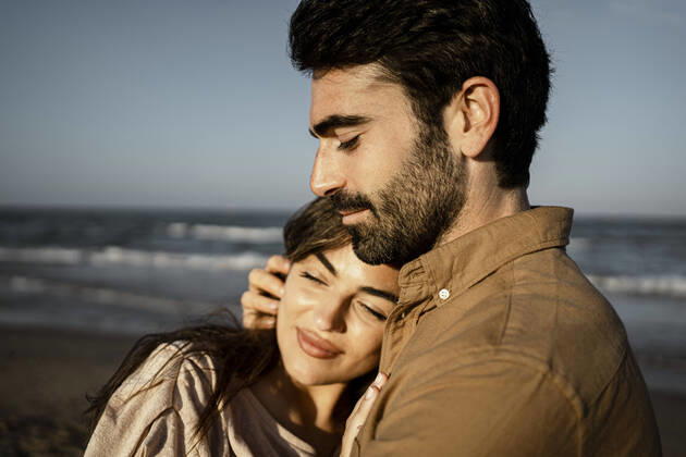 Smiling girlfriend embracing boyfriend at beach model released Symbolfoto RCPF01212