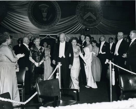 Washington, DC, January 21, 1957 -- Newly-inaugurated President Dwight David Eisenhower enters one of his Inaugural balls. The older woman with white gloves and black wrap to Eisenhower s right is Alice Roosevelt Longworth, daughter of President Theodore Roosevelt. Photo: Abbie Rowe NARA AbbiexRowexCollection 1063_05_Eisenhower Enters One of His Inaugural Balls