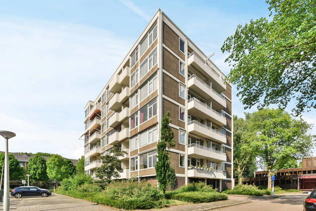 Creative design of masonry multistory building exterior with balconies between overgrown trees under light sky in Amsterdam North Holland, Property released CasaMedia_VanBoshuizenstraat465_2.jpg Copyright: xCasaxMediax Model Released
