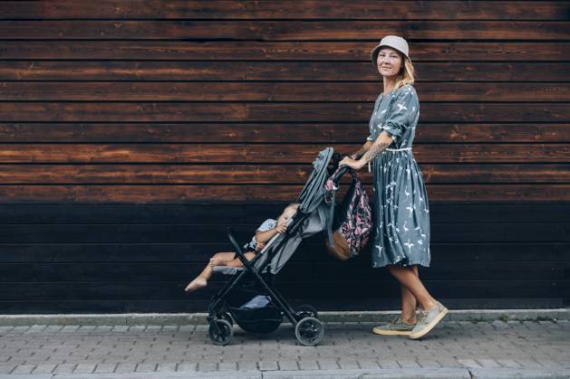 Mid adult woman pushing baby stroller on footpath model released Symbolfoto OMIF00073