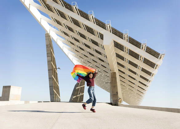 Woman holding rainbow flag near solar energy panel model released Symbolfoto VABF04360