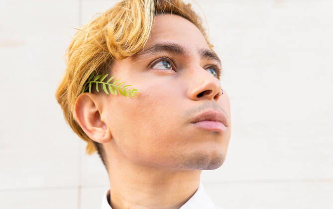 IMAGO Creative: Neue Fr?hlingsmode Thoughtful young male in formal shirt and small green twig on cheek looking into distance while standing on white background DavidMunoz_AlexUPC_21.jpg Copyright: xDavidxMunozx Model Released