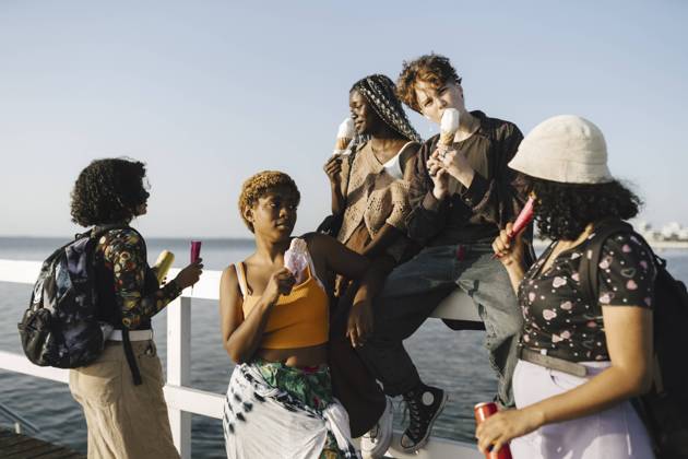 IMAGO Creative: Frauenmonat im März IMAGO Creative: Digitale Welt, Verzicht auf Technologie LGBTQIA multiracial friends eating ice creams on railing during sunny day Sweden, Malmo, model released Copyright: xMaskotx , MA89709