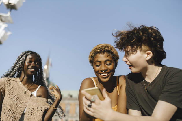 IMAGO Creative: Pride Month 2022, Engagement der Jugendlichen Teenage boy sharing smart phone to young friends on sunny day Sweden, Malmo, model released Copyright: xMaskotx , MA89727