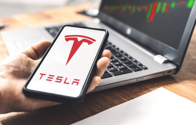 Tesla Auto Elektroauto Logo auf einem Smartphone, Handel an der Aktien Börse mit Anteilen der Tesla Aktie von Geschäftsführer Elon Musk, Online Trading mit Aktienanteilen xFOTOMONTAGEx