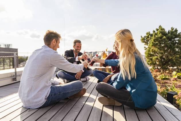 IMAGO Kreativ: Urbane Kultur - Sommer auf den Dächern Coworkers toasting drinks while sitting on rooftop model released property released, DIGF16937