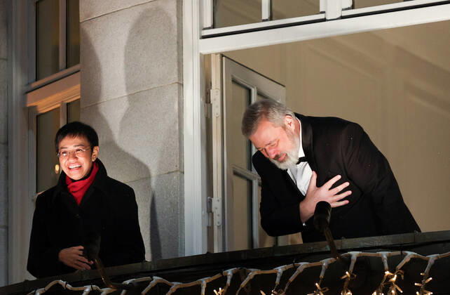 OSLO, NORWAY â€“ DECEMBER 10, 2021: Nobel Peace Prize winners, Filipino-American journalist, co-founder and CEO of Rappler Maria Ressa (L) Russian journalist, Novaya Gazeta editor-in-chief Dmitry Muratov greet the participants in a torchlight parade in honour of the 2021 Nobel Peace Prize winners from a balcony of the Grand Hotel. The Norwegian Nobel Committee has decided to award the Nobel Peace Prize for 2021 to Filipino-American journalist, co-founder and CEO of Rappler Maria Ressa and Russian journalist, Novaya Gazeta editor-in-chief Dmitry Muratov in recognition of their efforts to safeguard freedom of expression, which is a precondition for democracy and lasting peace . Sergei Bobylev TASS  TS11B678