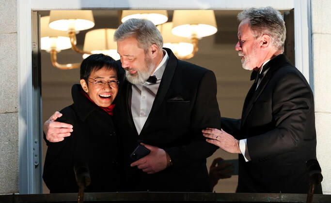 OSLO, NORWAY – DECEMBER 10, 2021: Nobel Peace Prize winners, Filipino-American journalist, co-founder and CEO of Rappler Maria Ressa, Russian journalist, Novaya Gazeta editor-in-chief Dmitry Muratov, and World Food Programme Executive Director David Beasley (L-R) greet the participants in a torchlight parade in honour of the Nobel Peace Prize winners from a balcony of the Grand Hotel. The Norwegian Nobel Committee has decided to award the Nobel Peace Prize for 2021 to Filipino-American journalist, co-founder and CEO of Rappler Maria Ressa and Russian journalist, Novaya Gazeta editor-in-chief Dmitry Muratov in recognition of their efforts to safeguard freedom of expression, which is a precondition for democracy and lasting peace . The World TS11B68D