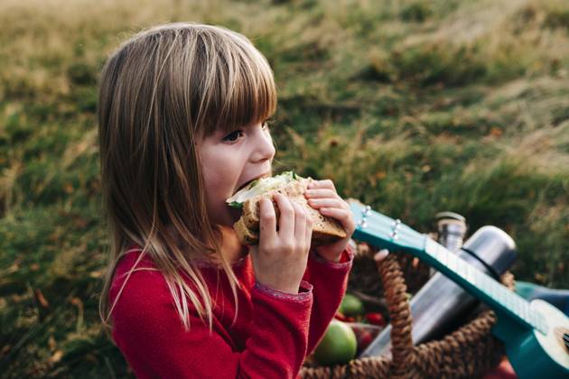 IMAGO Creative: Jahreszeit Frühling, Picknick Blond girl eating sandwich on grass model released, ASGF01670