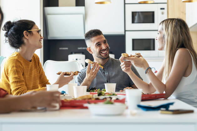 IMAGO Creative: Gesellschaft, Integration Smiling businessman with pizza talking to businesswoman at office cafeteria model released property released, JSRF01725