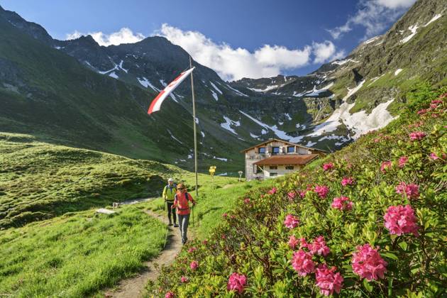 Man and woman hiking in Virgental during spring with Bergerseehutte in background model released, ANSF00090