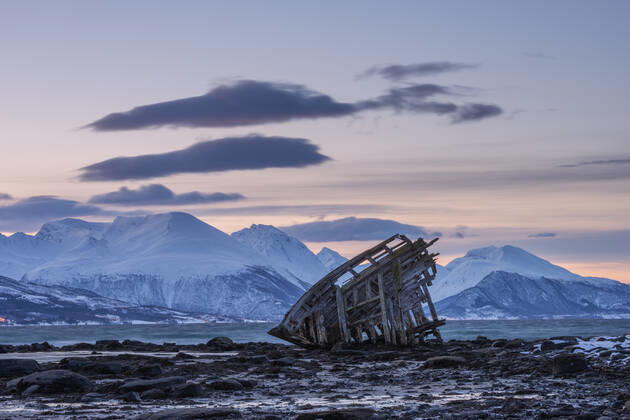 Shipwreck lying on shore of secluded Fjord at winter dawn, RUEF03444