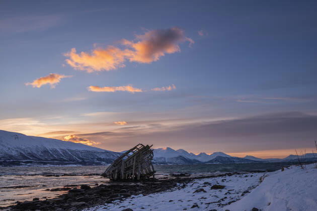 Shipwreck lying on shore of secluded Fjord at winter dawn, RUEF03449