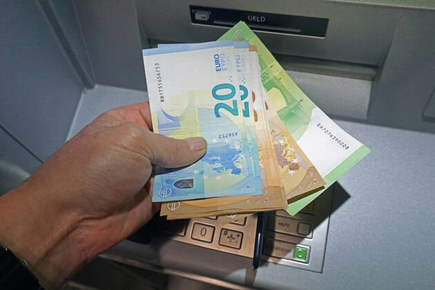 Bargeldversorgung aus einem Automat Eine Person holt an einem Geldautomaten eine größere Menge Bargeld in 100, 50 und 20 Euro Geldscheinen ab