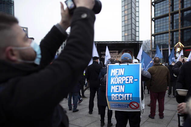 Protest AfD - Gegen Impfplicht DEU, Deutschland, Germany, Berlin, 11.12.2021 Demonstrant mit Plakat Mein Koerper Mein Recht Freies Land Freie Impfentscheidung vor Transparent Die Jugend Steht Auf Telegram Impfstreik auf einer Kundgebung und Demonstration der Jungen Alternative JA, die Jugendorganisation‹ der rechtsextremen Partei Alternative fuer Deutschland AfD gegen eine Impfpflicht und die Coronapolitik der Bundesregierung unter dem Motto Impfstreik Deutschland im Regierungsviertel in Berlin. Der Protest ist gegen das Impfen gegen Corona Covid-19 und eine moegliche Impfpflicht wird unterstuetzt von sog. Querdenker und Rechtsradikalen. Junge Alternative fuer Deutschland. en: Protester with poster Mein Koerper Mein Recht Free Land Free v