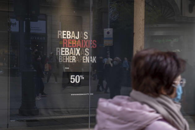 January 9, 2022, Barcelona, Catalonia, Spain: A woman wearing a facemask walks past a store window advertising up to 50% discount on winter sales..Despite the strong increase in contagions from the new Omicron variants, Barcelona fully enters the winter sales with entry to establishments restricted to a capacity of 70% Barcelona Spain - ZUMAs197 20220109_zaa_s197_114 Copyright: xPacoxFreirex