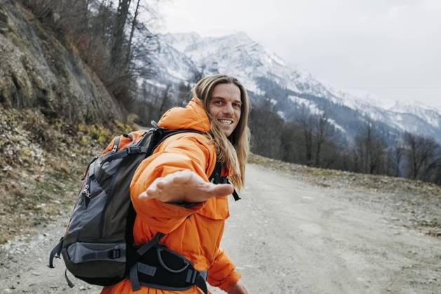 IMAGO Creative: 2022 Sport Favoriten IMAGO Creative: Wintersport, Urlaub Cheerful man in orange jacket walking on mountain road model released, OMIF00399