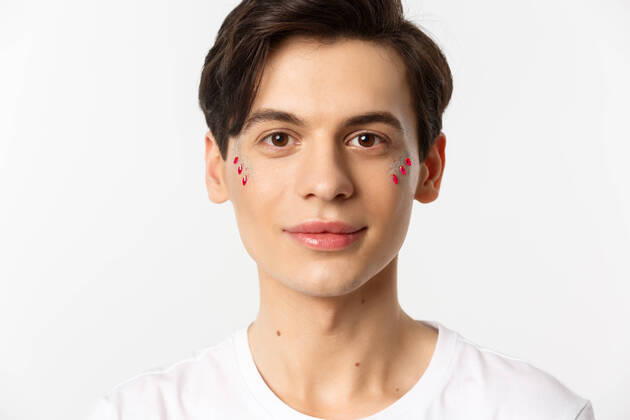 IMAGO Creative: Pride Month 2022, Engagement der Jugendlichen People, lgbtq and beauty concept. Close-up of happy queer guy with applied lip gloss and glitter, smiling and looking at camera, standing over white background People, lgbtq and beauty concept. Close-up of happy queer guy with applied lip gloss and glitter, smiling and looking at camera, standing over white background. Copyright: xSevaxLevitskyx 43847794