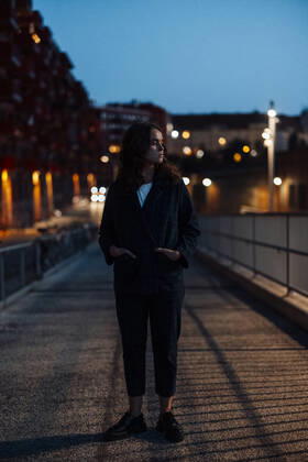Young woman with hands in pockets standing on city street at night model released, GUSF06852