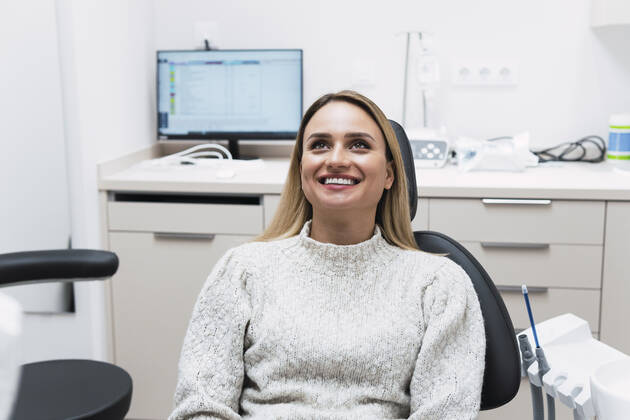Smiling young woman sitting on dentist chair at clinic model released property released, PNAF03067