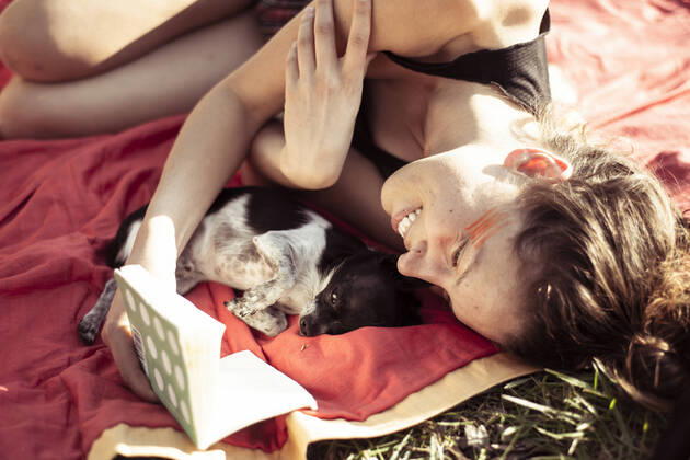 IMAGO Creative: Jahreszeit Frühling, Picknick Beautiful woman smiles and reads to tiny puppy on an afternoon picnic Grünheide (Mark), BB, Germany CR_PIDODS220304-368437-01 ,model released, Symbolfoto