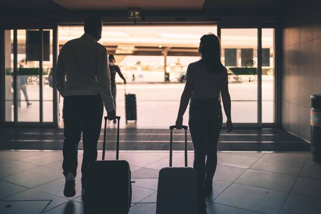 Ein paar Freunde mit Gepäck und Schutzmasken verlassen den Flughafen Copyright: imageBROKER/EunikaxSopotnicka ibxeso08189396
