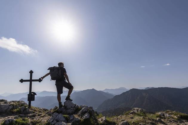 Germany, Bavaria, Sun shining over silhouette of male hiker standing by Fockenstein summit cross model released, Symbolfoto, FOF13102