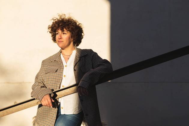 Confident female in trendy outfit looking into distance while leaning on railing near white wall with shadow on sunny street DavidMunoz_AnaSpring_29.jpg Copyright: xDavidxMunozx Model Released