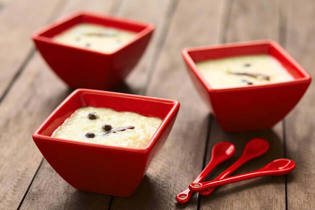 Three red bowls of the Ecuadorian dessert called morocho (coarsely ground white corn) cooked with milk, sugar and spices (cinnamon and allspice), similarly to rice pudding (Selective Focus, Focus on the middle of the lower morocho) , 14343508.jpg, morocho, cooked, sweet, dessert, pudding, food, milk, spice, condiment, cinnamon, allspice, newspice, Jamaica pepper , prepared, Ecuador, Ecuadorian, traditional, corn, maize, ground, coarse, kernel, porridge, bowl, red, horizontal, white,