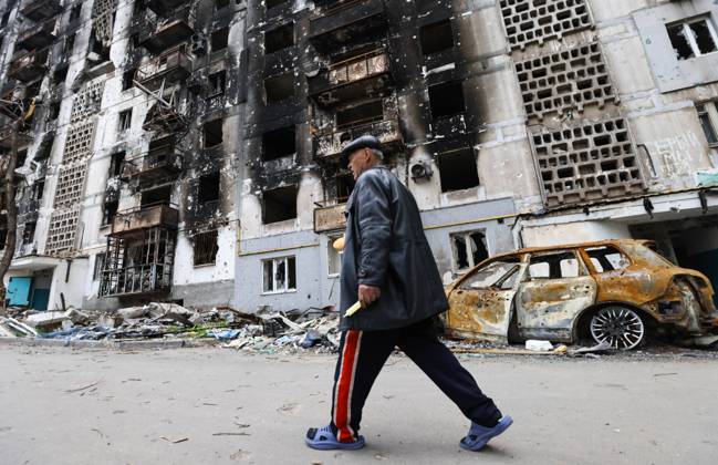 DONETSK REGION, UKRAINE - MAY 5, 2022: A local man walks past an apartment building damaged by shelling in the embattled city of Mariupol. With tension escalating in Donbass in February, the Russian Armed Forces launched a special military operation in Ukraine in response to appeals for help from the Donetsk and Lugansk People s Republics. Peter Kovalev TASS  TS12FC10