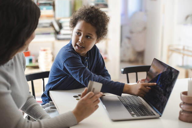 Son pointing at laptop screen while looking at mother holding credit card Sweden, Stockholm, model released, property released Copyright: xMaskotx , MA93693